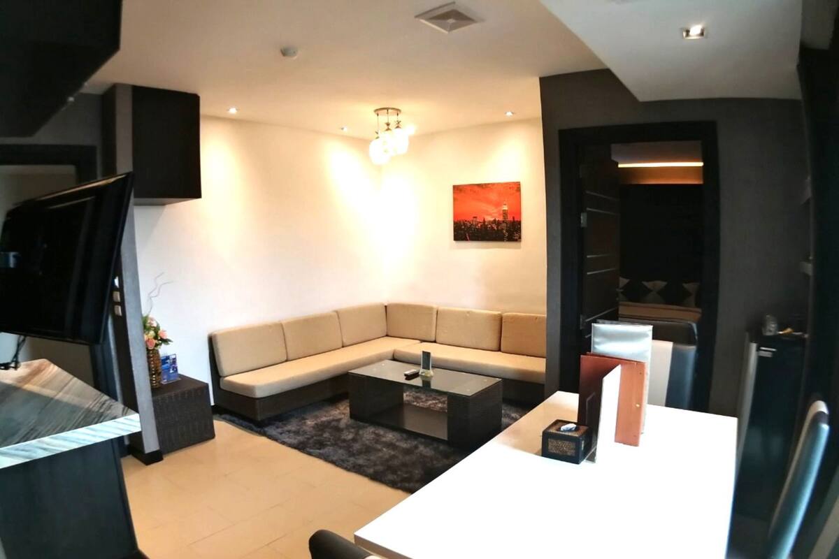 Una sala moderna con un sofá modular, una mesa de centro y un televisor montado en la pared.