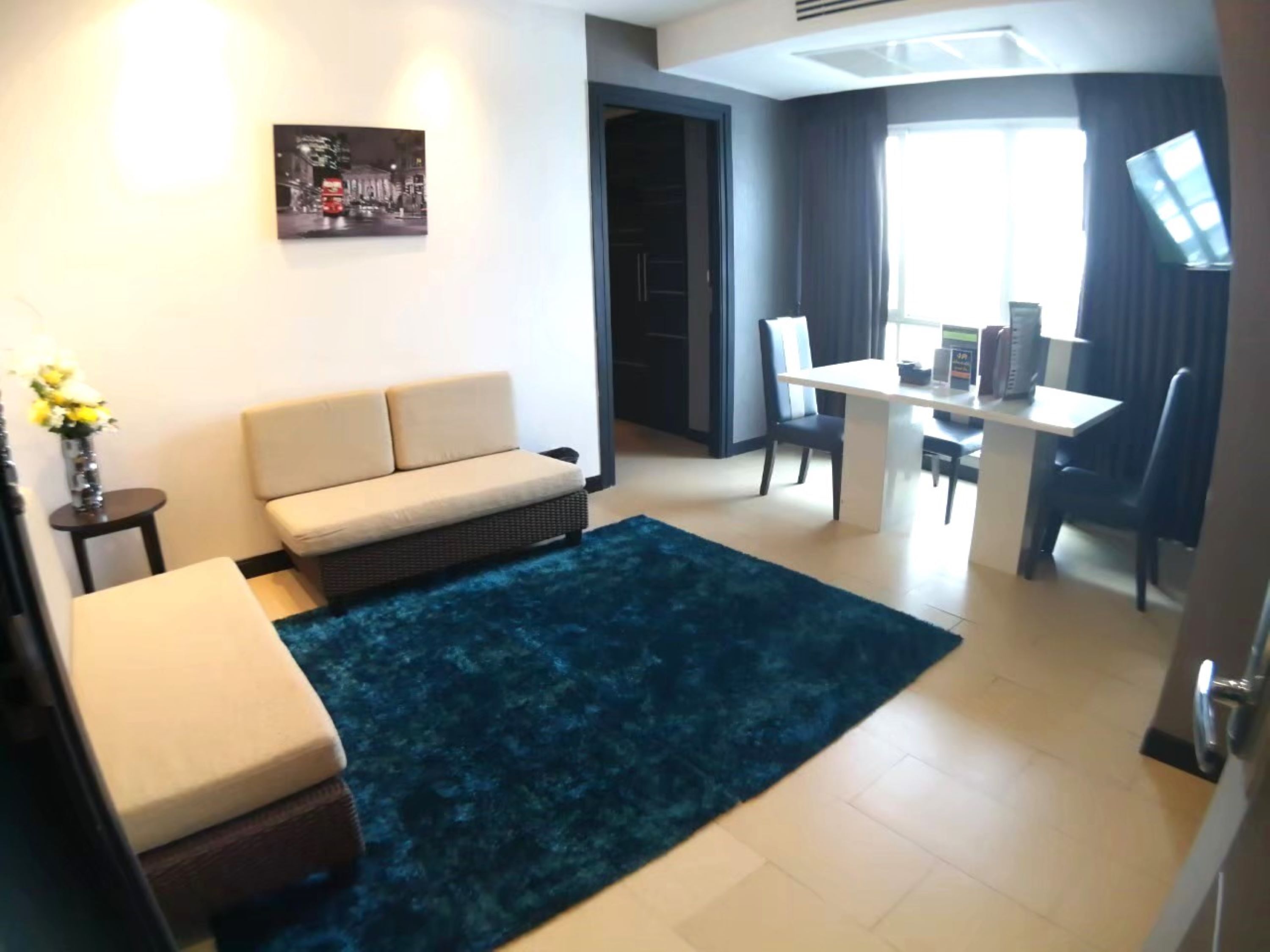 A modern living room with a sofa, a dining table, and a blue rug.
