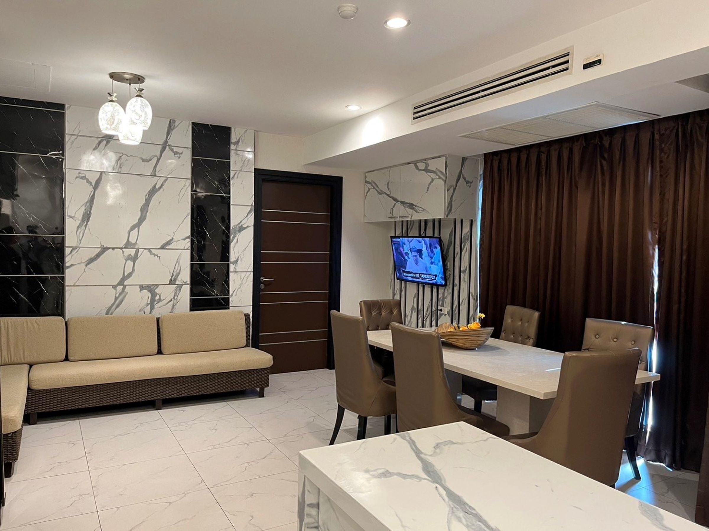 A modern living room with a sofa, dining table, chairs, and a TV.