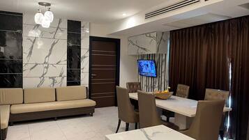 A modern living room with a sofa, dining table, chairs, and a TV.