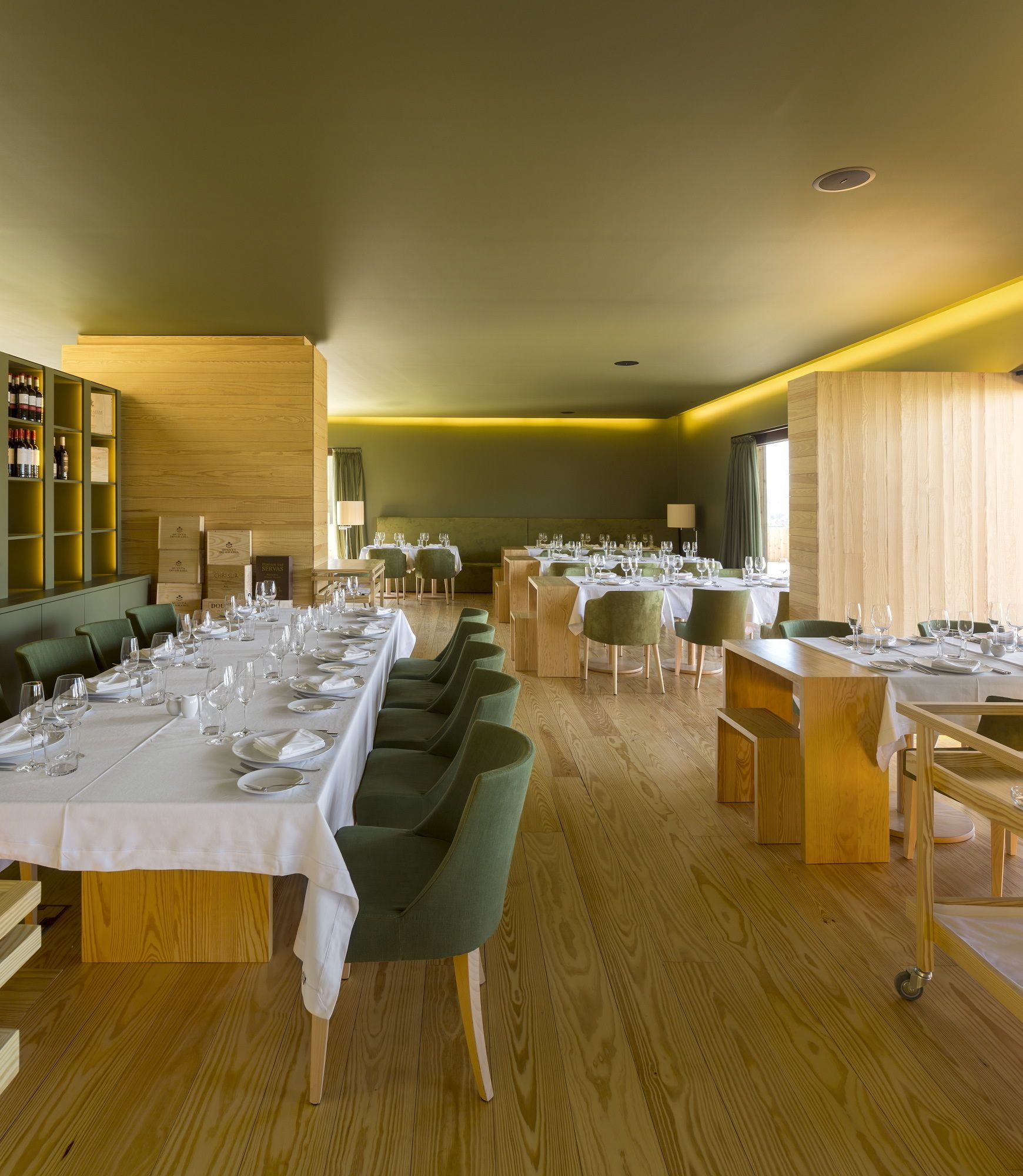 A restaurant with multiple tables set for dining, wooden flooring, and a warm ambiance.