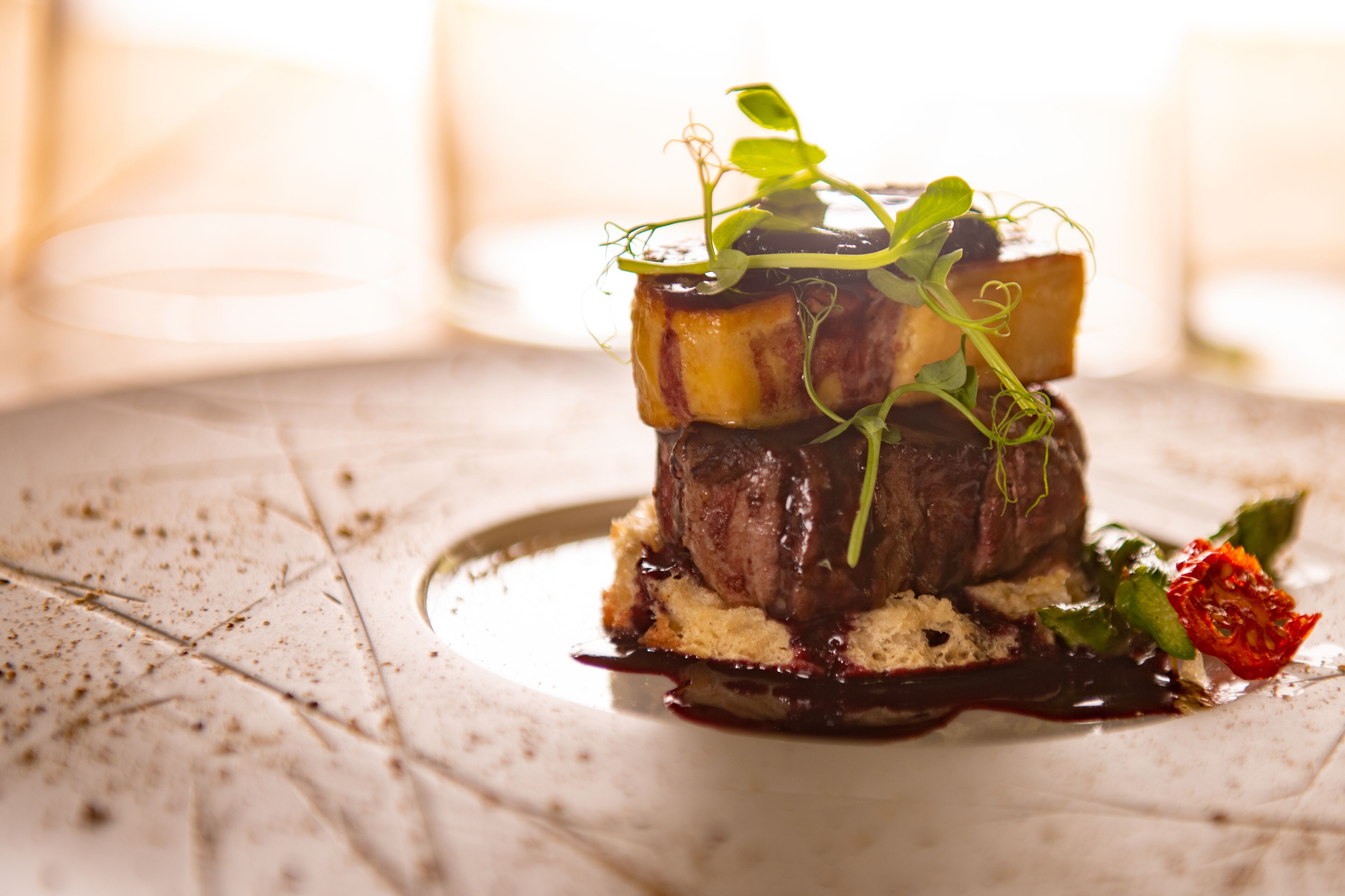 A plated dish with a steak, vegetables, and sauce.