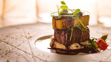 A plated dish with a steak, vegetables, and sauce.