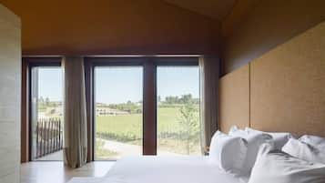 Un dormitorio con una cama grande, vistas a un viñedo y una puerta corredera que da a un espacio al aire libre.