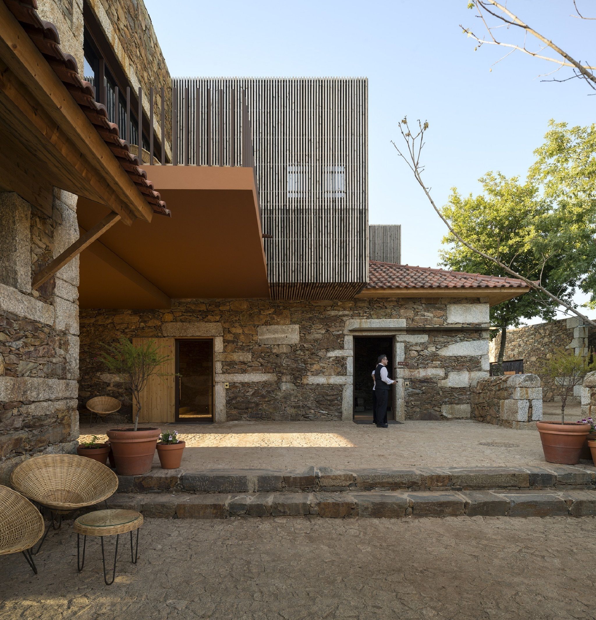 A stone building with a modern extension featuring vertical slats.