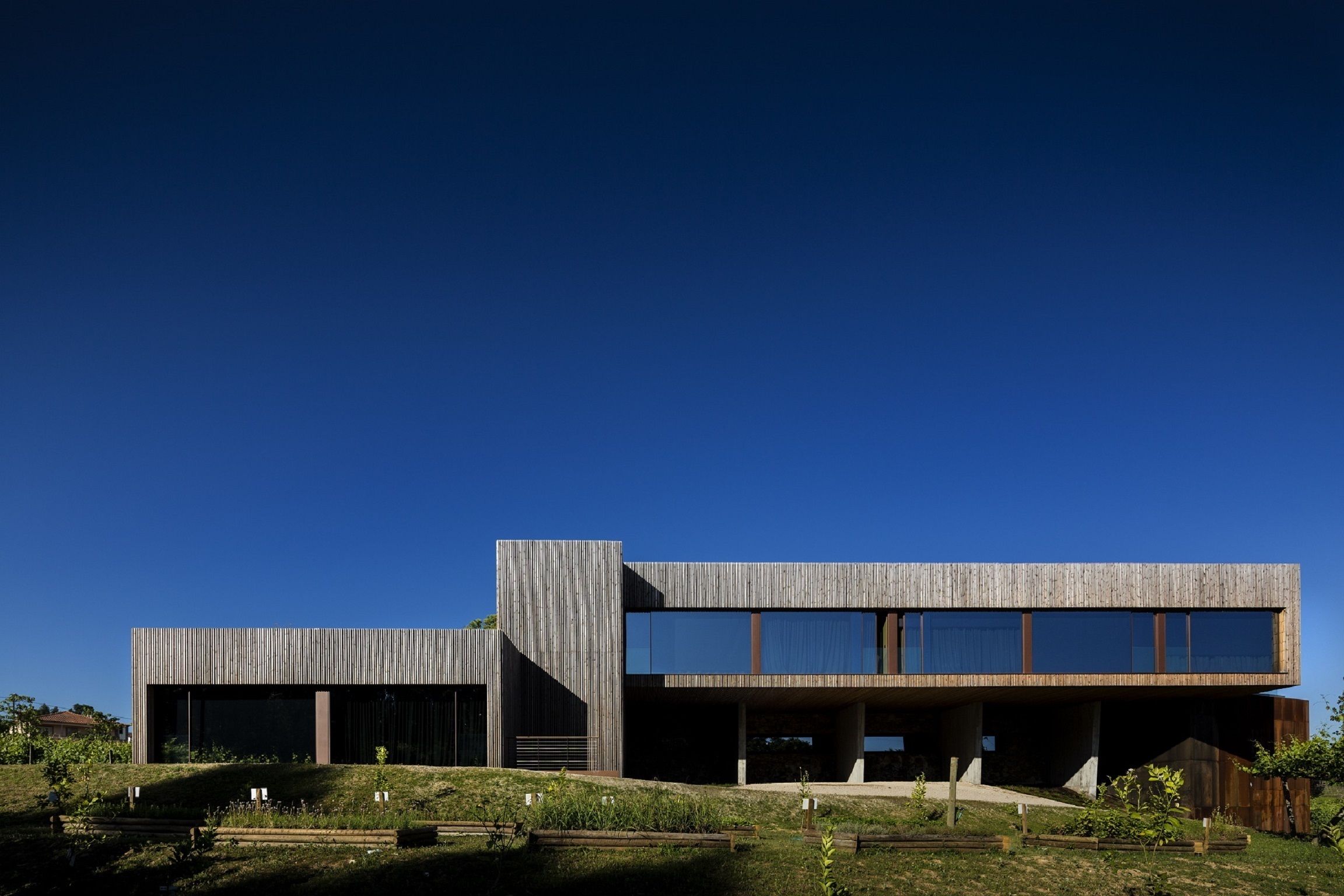 Un edificio moderno con techo plano, ventanas amplias y un lateral inclinado.