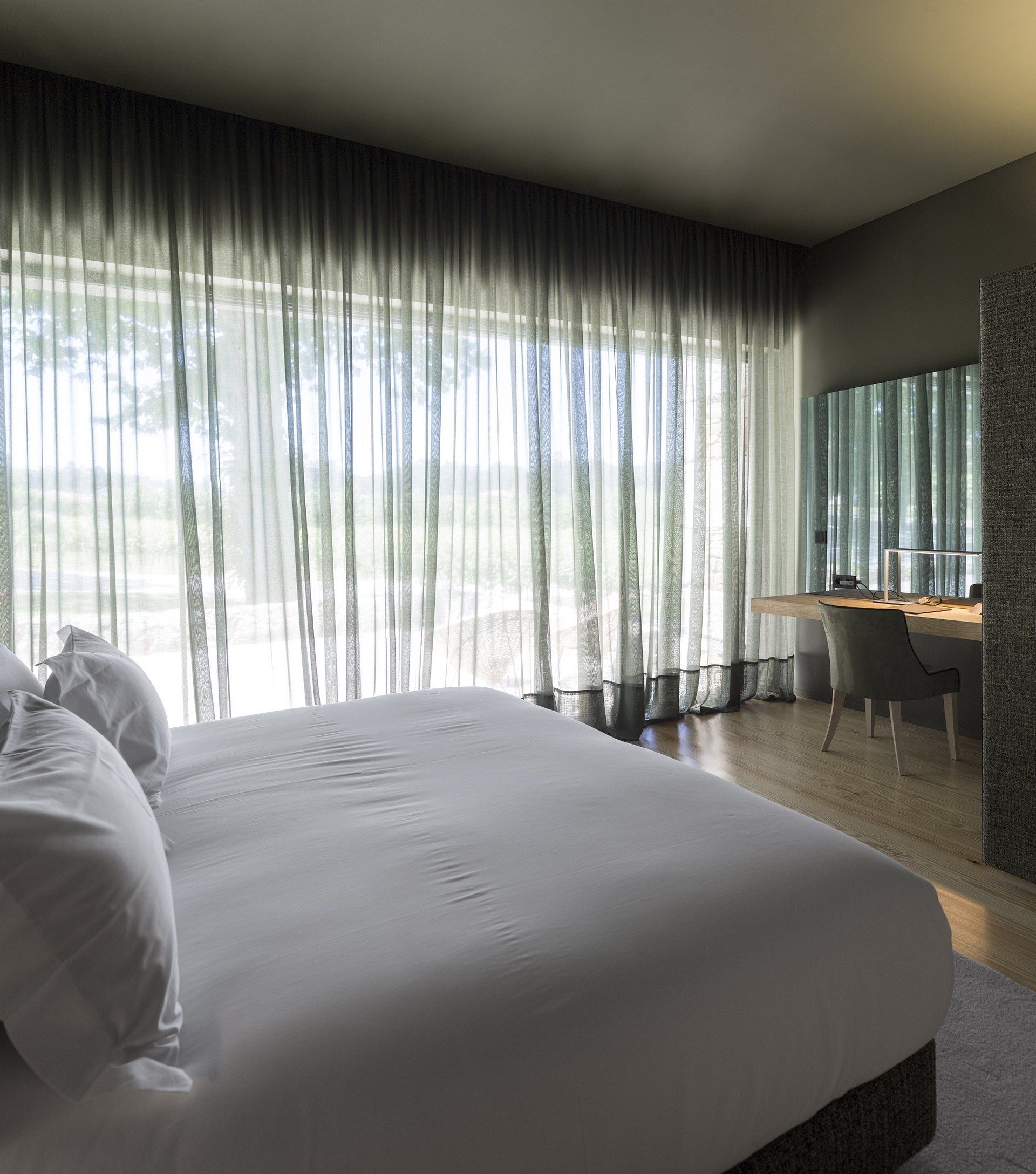 Een moderne slaapkamer met een groot bed, een bureau en een stoel.