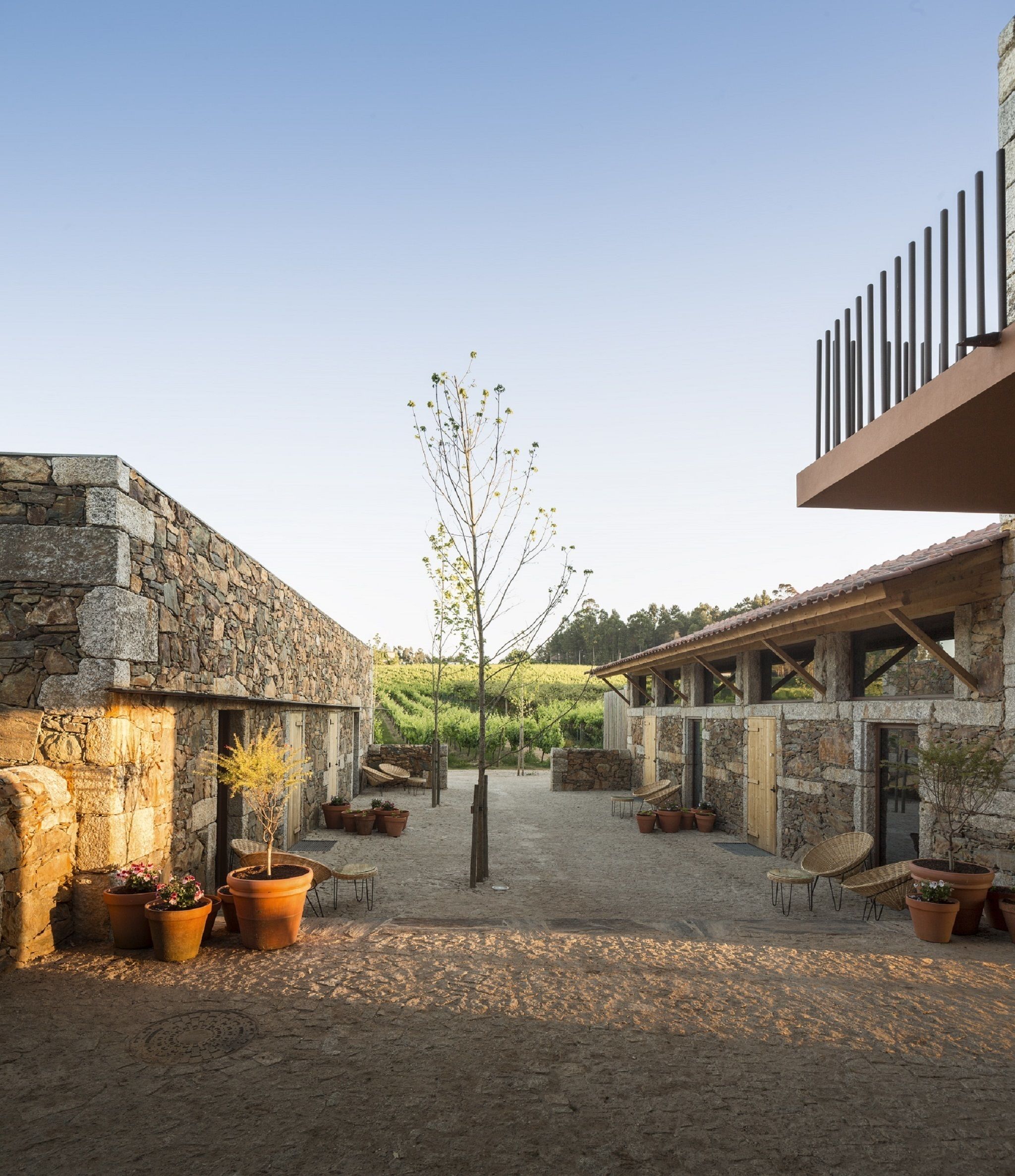 A courtyard with stone walls, potted plants, and outdoor seating.