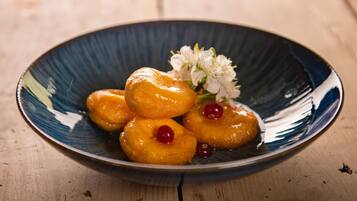 A plate of glazed donuts with cherries on a wooden table.