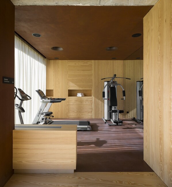 A gym with cardio machines, weight training equipment, and a wooden interior design. - Monverde - Wine Experience Hotel by Unlock Hotels (Amarante)