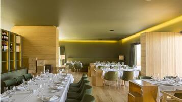 A dining area with multiple tables set for guests, wooden paneling on the walls, and a wine rack with bottles.