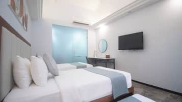 Une chambre d’hôtel avec deux lits, un bureau, une chaise, une télévision et une salle de bain avec une porte bleue.