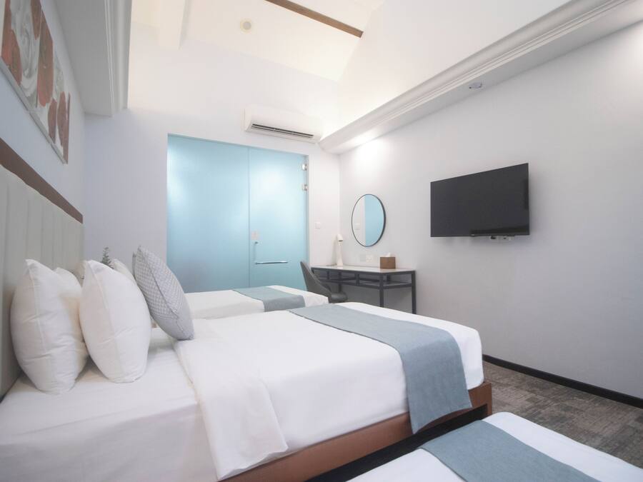 Habitación de hotel con dos camas, un escritorio, una silla, un televisor y un baño con puerta azul.