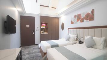 A hotel room with two beds, a TV, a desk, and a bathroom.