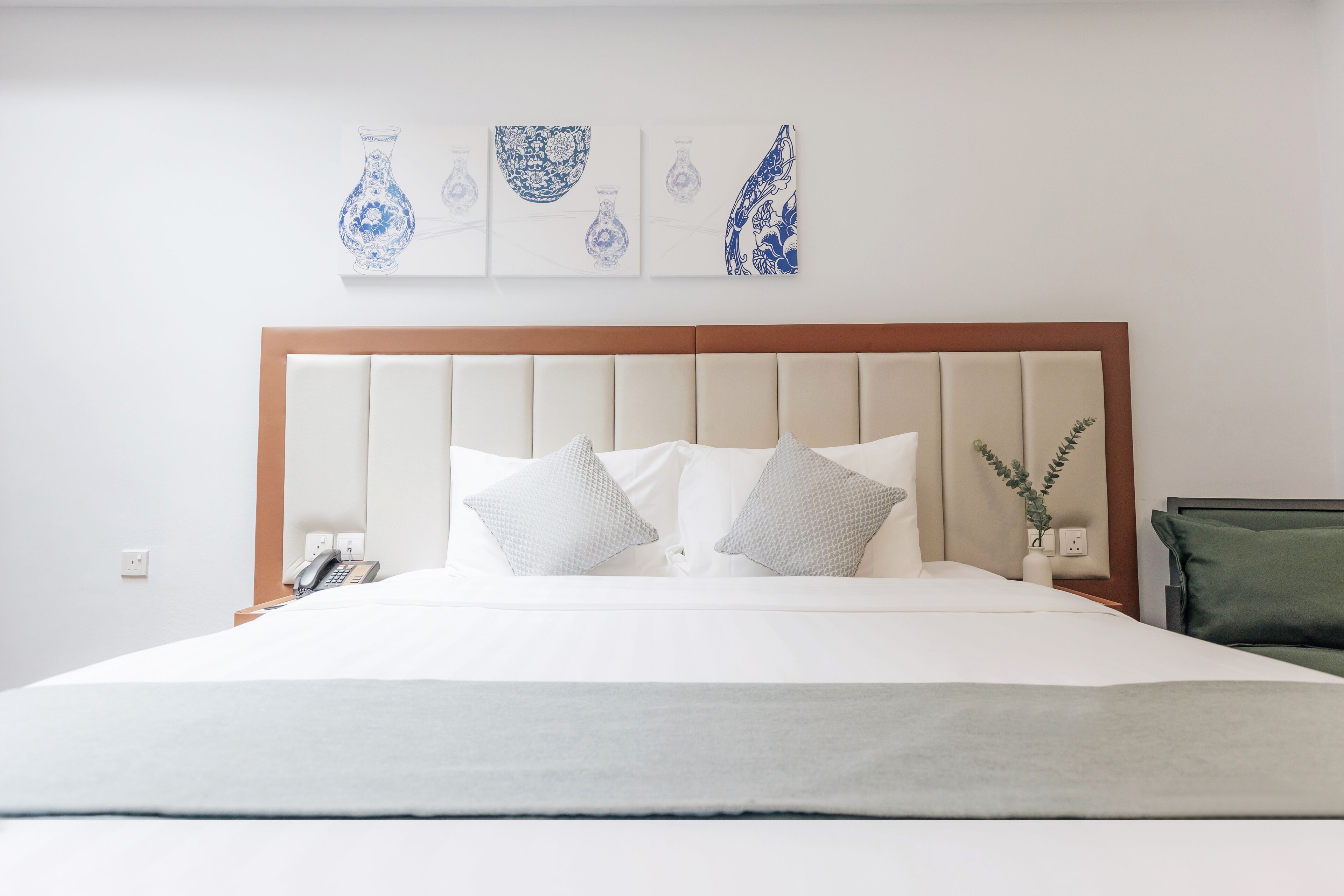 Una cama bien hecha con cabecera de madera, ropa de cama blanca y varios almohadones.