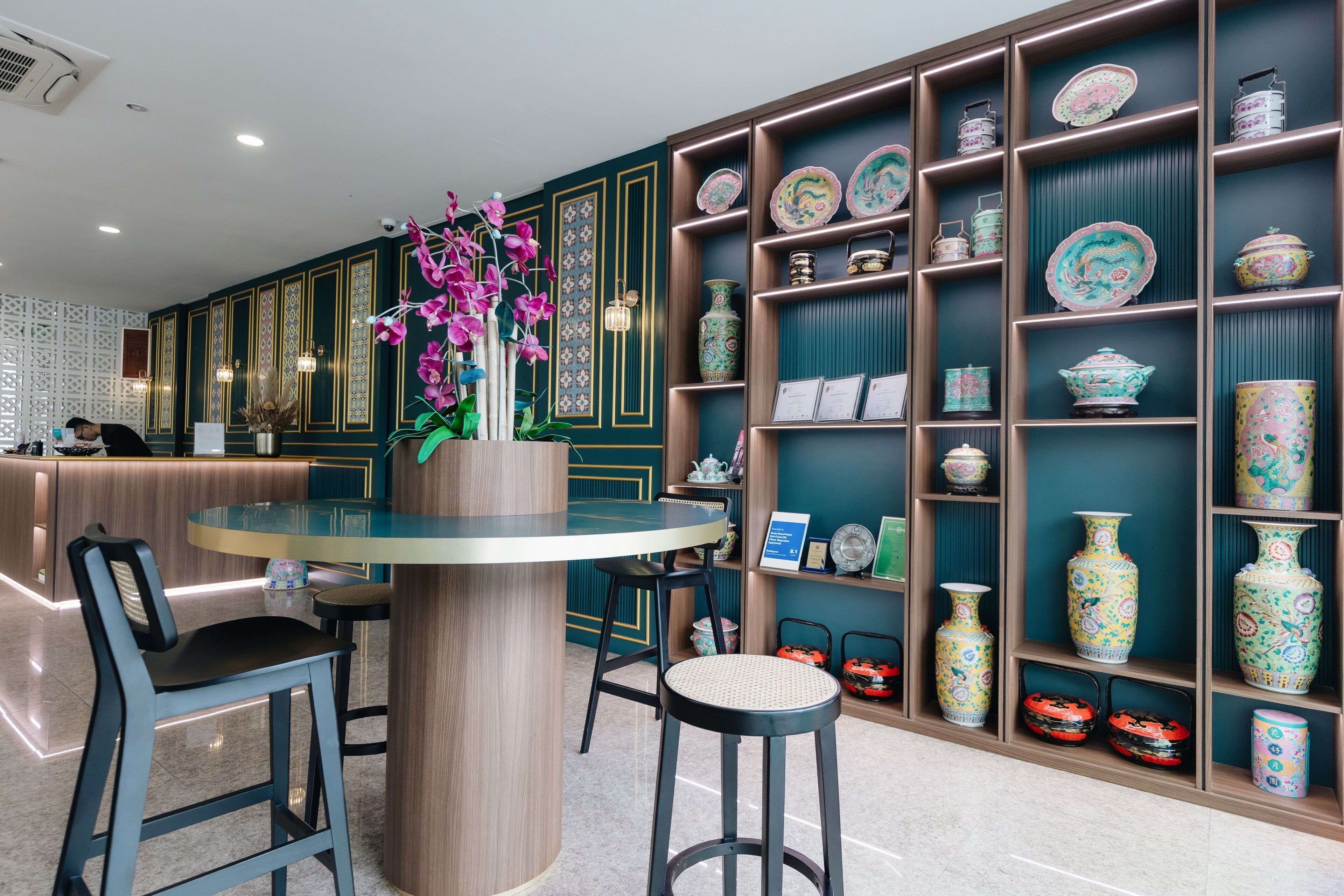 Un interior moderno con una mesa redonda, taburetes de bar y un florero decorativo con flores.