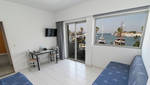 A hotel room with a balcony, a desk, two beds, and a TV. - Jasmine Hotel Apartments (Kos)