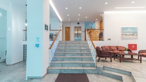 A hotel lobby with a staircase, a reception desk, and a seating area. - Jasmine Hotel Apartments (Kos)