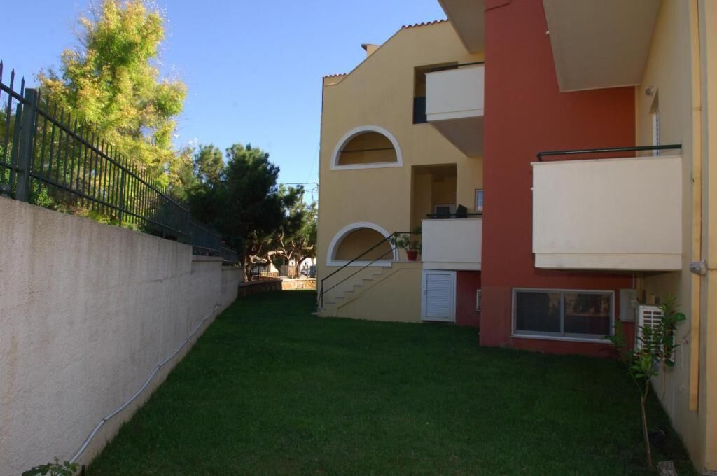 Un edificio de dos pisos con fachada roja y beige, un pequeño balcón y una escalera que conduce al piso superior.