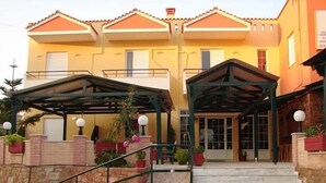 A hotel entrance with a covered walkway, stone steps, and potted plants. - Sunrise Hotel (Chios)