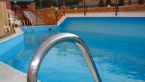 A swimming pool with a metal ladder leading into the water. - Sunrise Hotel (Chios)