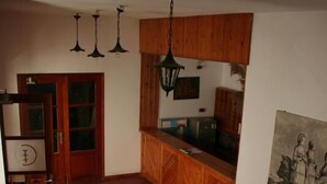 Una stanza con una scala in legno, un angolo cottura con mobili in legno e un tavolo da pranzo.