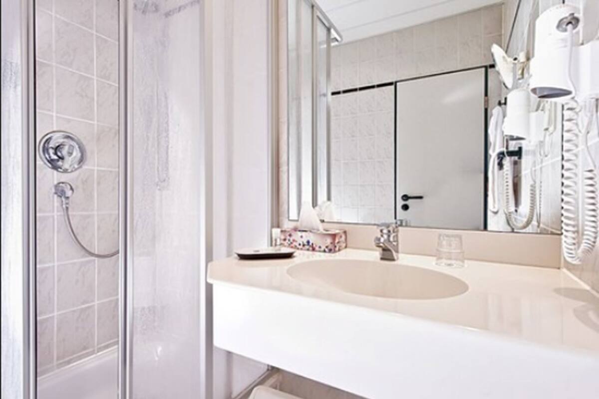 A modern bathroom with a glass shower enclosure, a white sink, and a large mirror.