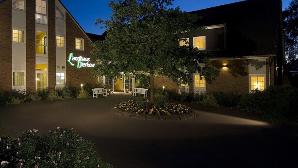 Um hotel com design moderno, exibindo uma placa com o nome 'Landhaus Dierkow' e uma entrada bem iluminada.
