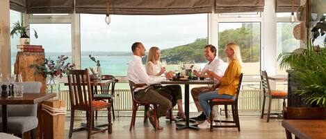 A dining area with a large table and chairs, overlooking a scenic view.