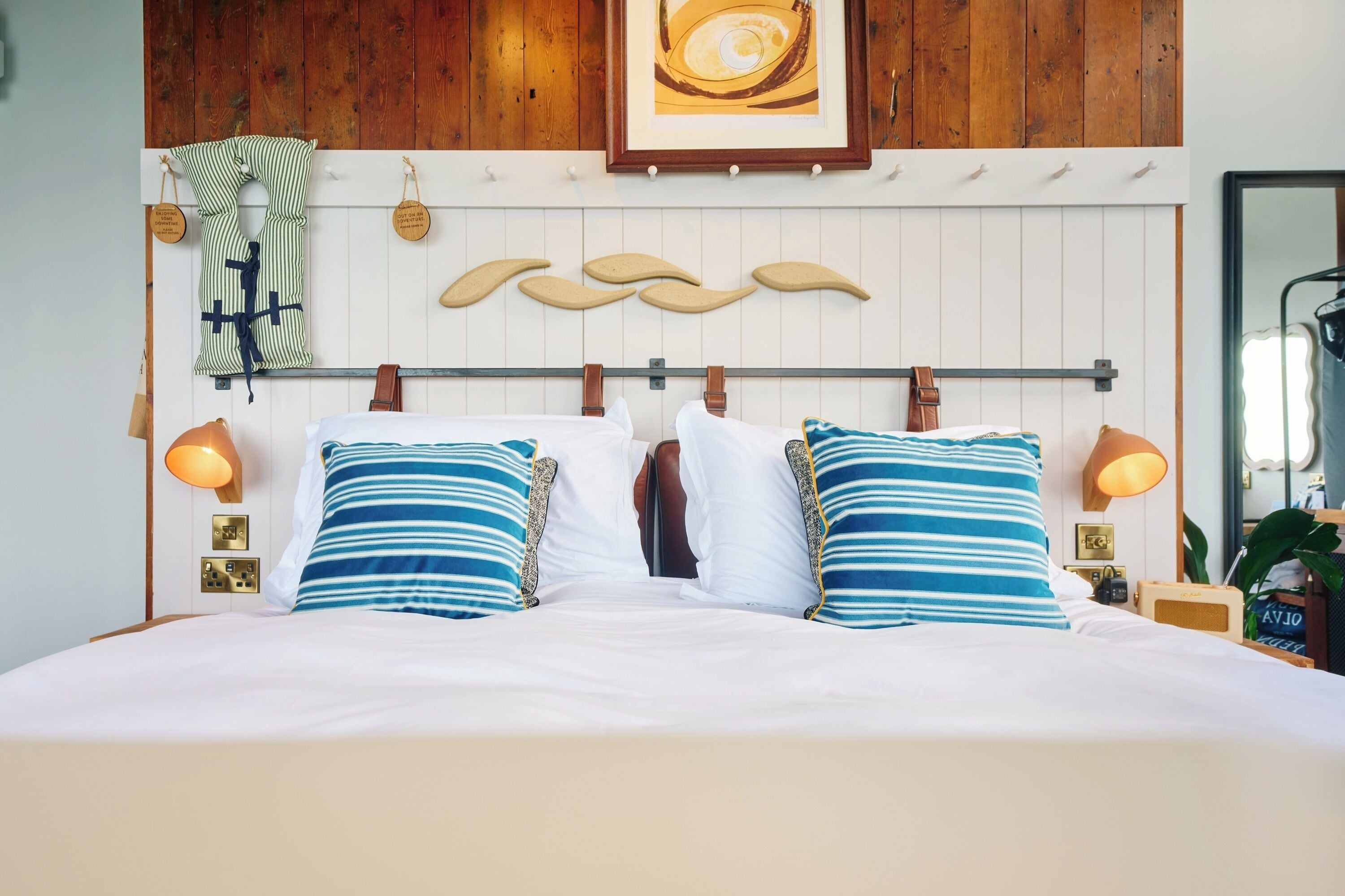 A bed with white bedding, striped pillows, and a wooden headboard.