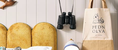 A neatly arranged bedroom with a bed, bedside lamp, radio, and a wall-mounted bag.