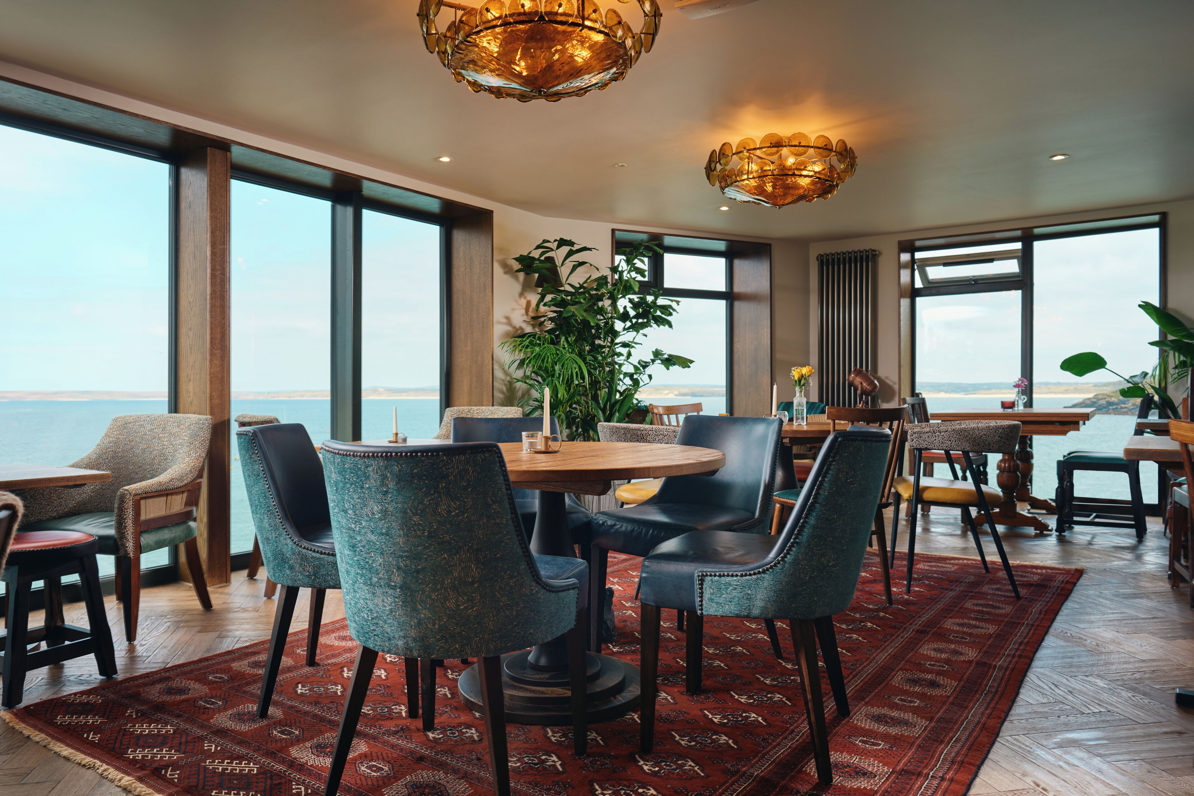 A spacious dining area with large windows, a view of the sea, and modern furniture.