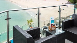 Un balcón con muebles de mimbre con vistas a la playa.
