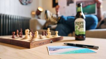 A chessboard, a bottle of beer, a pen, and a postcard on a table.