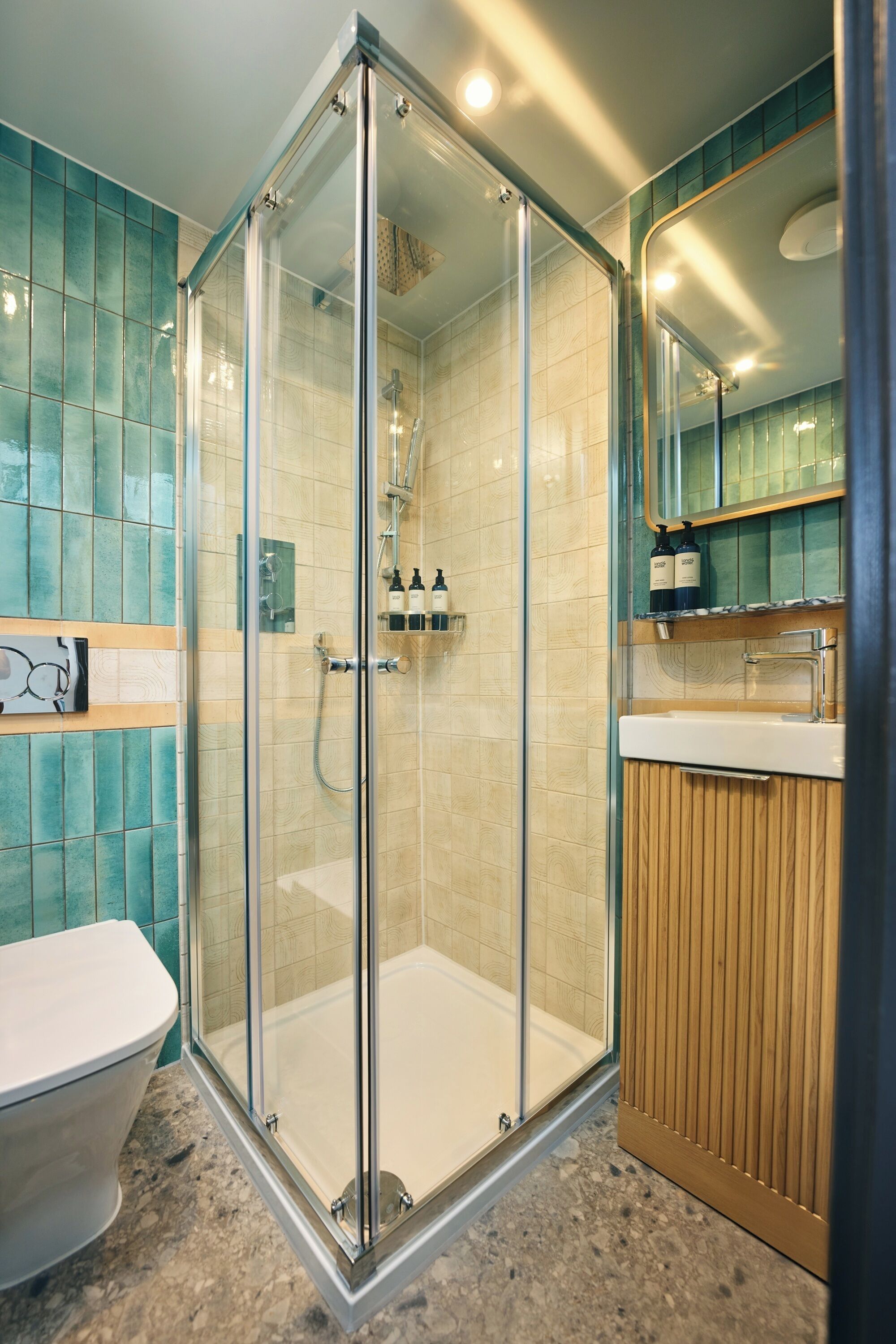 A modern bathroom with a glass-enclosed shower, a white toilet, and a wooden vanity with a mirror.