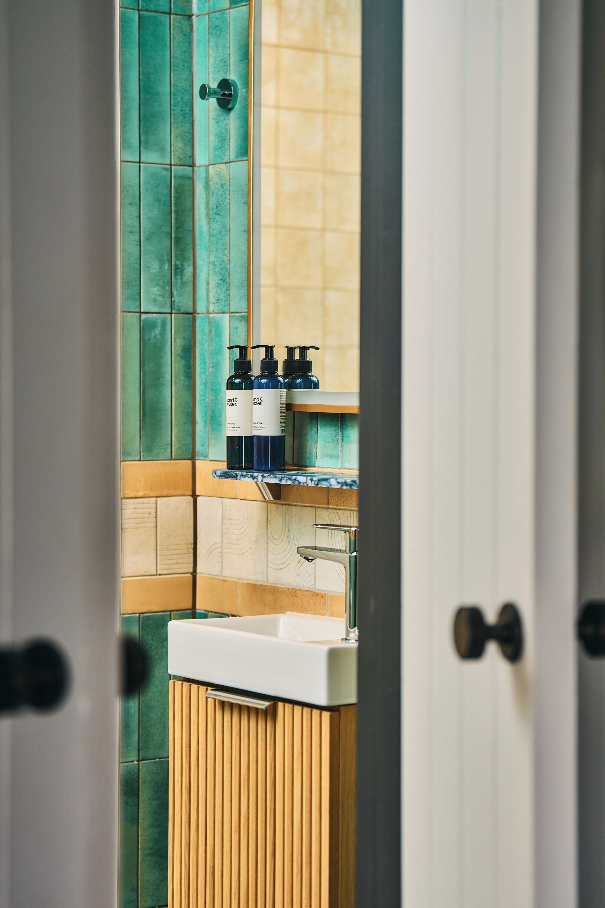A bathroom with a sink, a mirror, and a door.