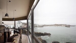 Un restaurante frente al mar, con vista al océano y un pueblo lejano.