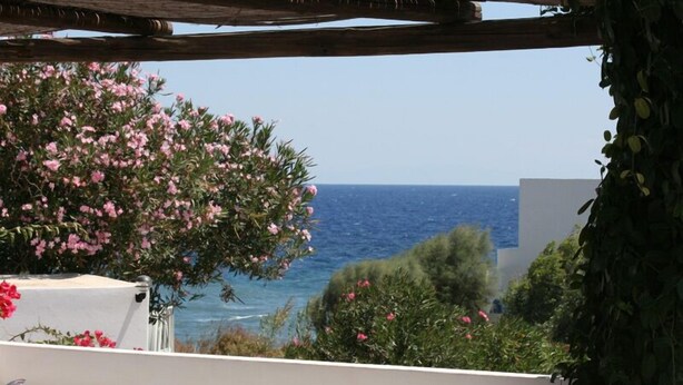 A balcony with a view of the sea, a table, chairs, and a pergola. - Pensione La Nassa (Lipari)