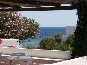 A balcony with a view of the sea, a table, chairs, and a pergola. - Pensione La Nassa (Lipari)