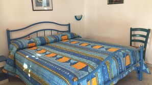 A bedroom with a bed, a chair, and two framed pictures on the wall. - Pensione La Nassa (Lipari)