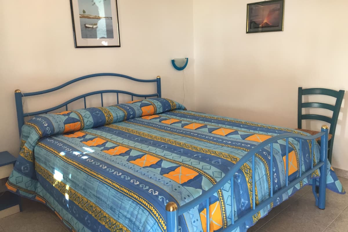 Un dormitorio con una cama, una silla y dos cuadros en la pared.