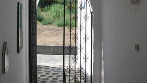An arched doorway with a metal gate, leading to an outdoor area with a stone pathway and greenery. - Pensione La Nassa (Lipari)