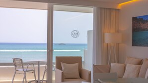 Habitación de hotel con balcón y vista al océano, que incluye un sofá, una mesa y una silla.