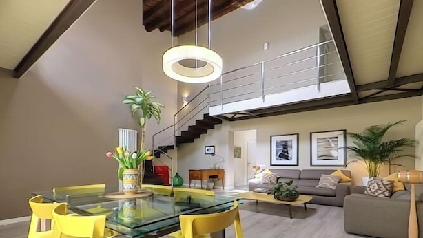 A spacious living area with a high ceiling and a staircase leading to an upper level. - B&B Cubbaita (Palermo)