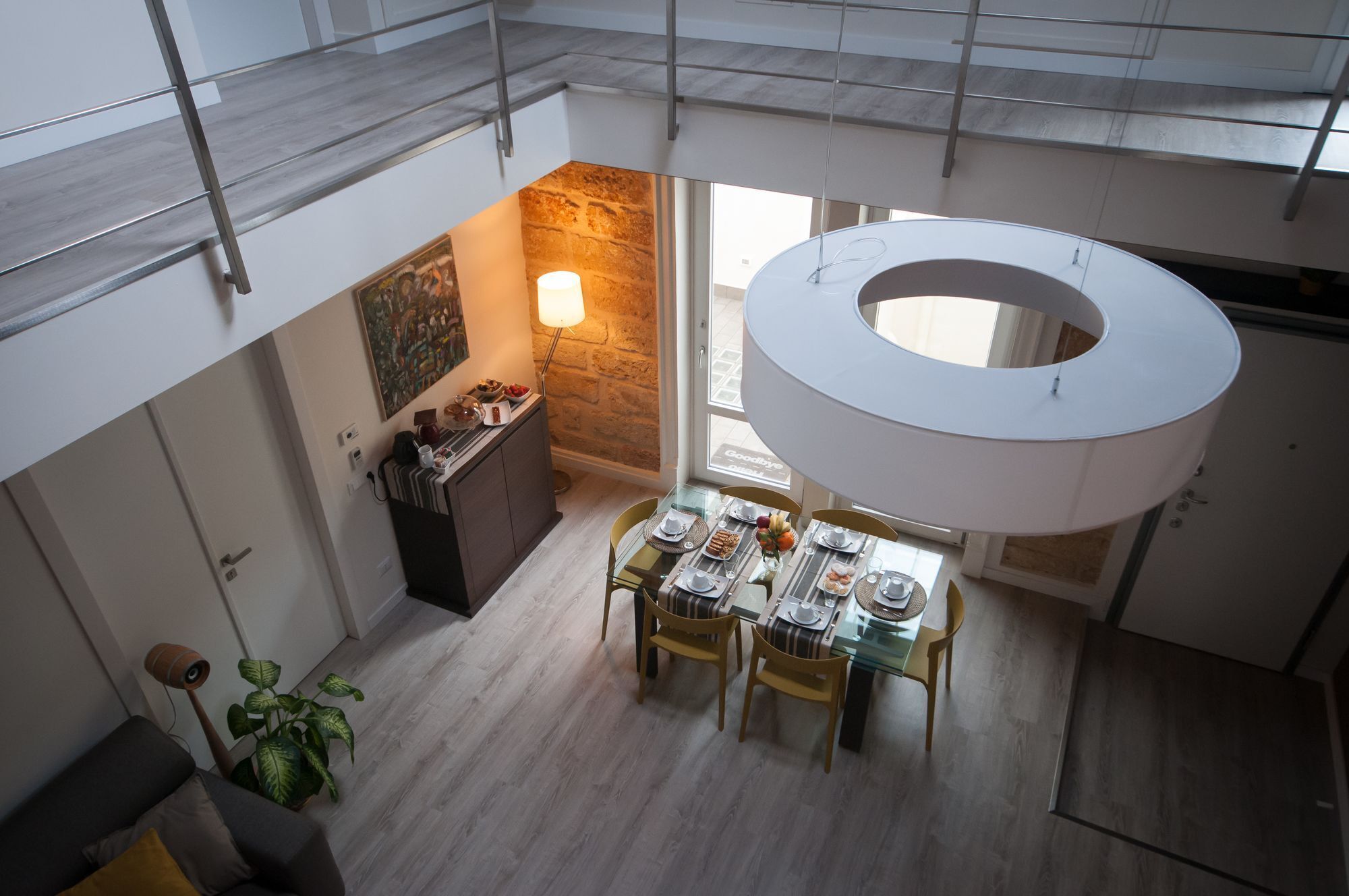 A modern dining area with a glass table, chairs, and a unique circular ceiling light fixture.