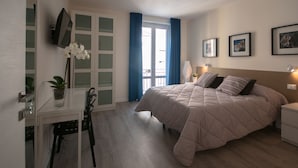 A bedroom with a bed, a desk, a chair, a TV, and a window with curtains. - B&B Cubbaita (Palermo)