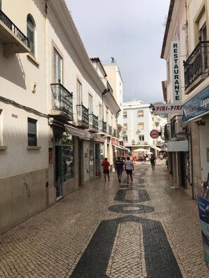 Una calle estrecha con comercios y el letrero de un restaurante.