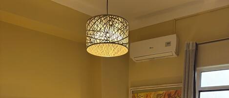 Hotelkamer met een groot bed, hoofdeinde, bedlampje, klein tafeltje met een lamp, schilderij aan de muur en raam met uitzicht op een groen gebied.