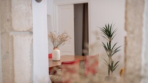 A dining area with a wooden table, red chairs, a white vase with dried flowers, and a potted plant. - Blasius Residence (Dubrovnik)