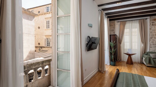 A room with a bed, a TV, a small table, and a potted plant. - Blasius Residence (Dubrovnik)